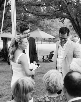 Wedding ceremony outdoors with guests and a couple exchanging vows.