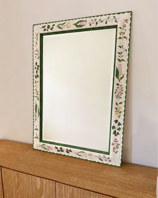 Decorative mirror with floral frame on a wooden surface