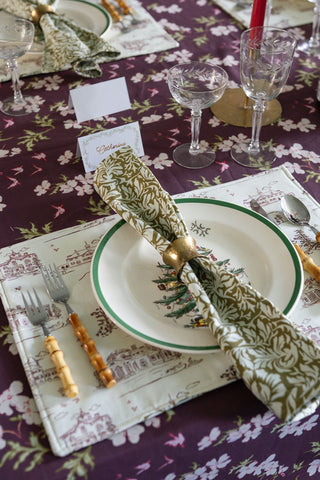Table setting with floral tablecloth, plates, cutlery, and decorative napkin.