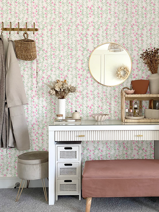 Room interior with floral wallpaper, white desk, pink bench, and decorative items.