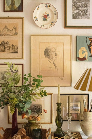Wall with framed artwork, a lamp, and decorative items including a plant.