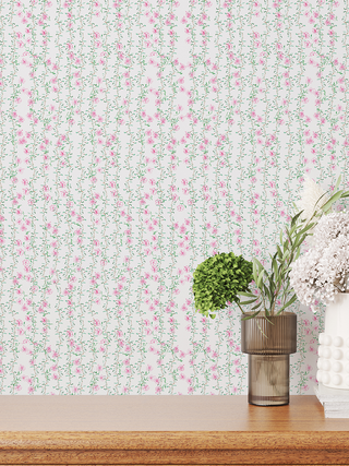 Floral wallpaper with pink and green flowers on a white background, with decorative plants on a wooden surface.