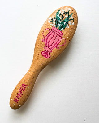 Wooden hairbrush with floral design and 'Harper' branding on a white background