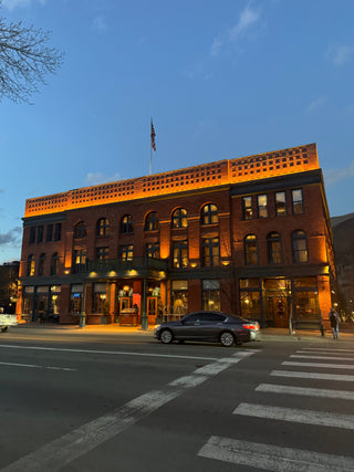 hotel Jerome aspen building with street-level shops at dusk, illuminated by warm lights.