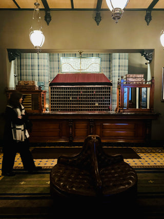 Vintage interior with wooden desk, plaid curtains, and a person observing.hotel-jerome-photo-shoot-creative-direction