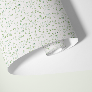 Roll of wallpaper with a subtle green floral pattern on a white background